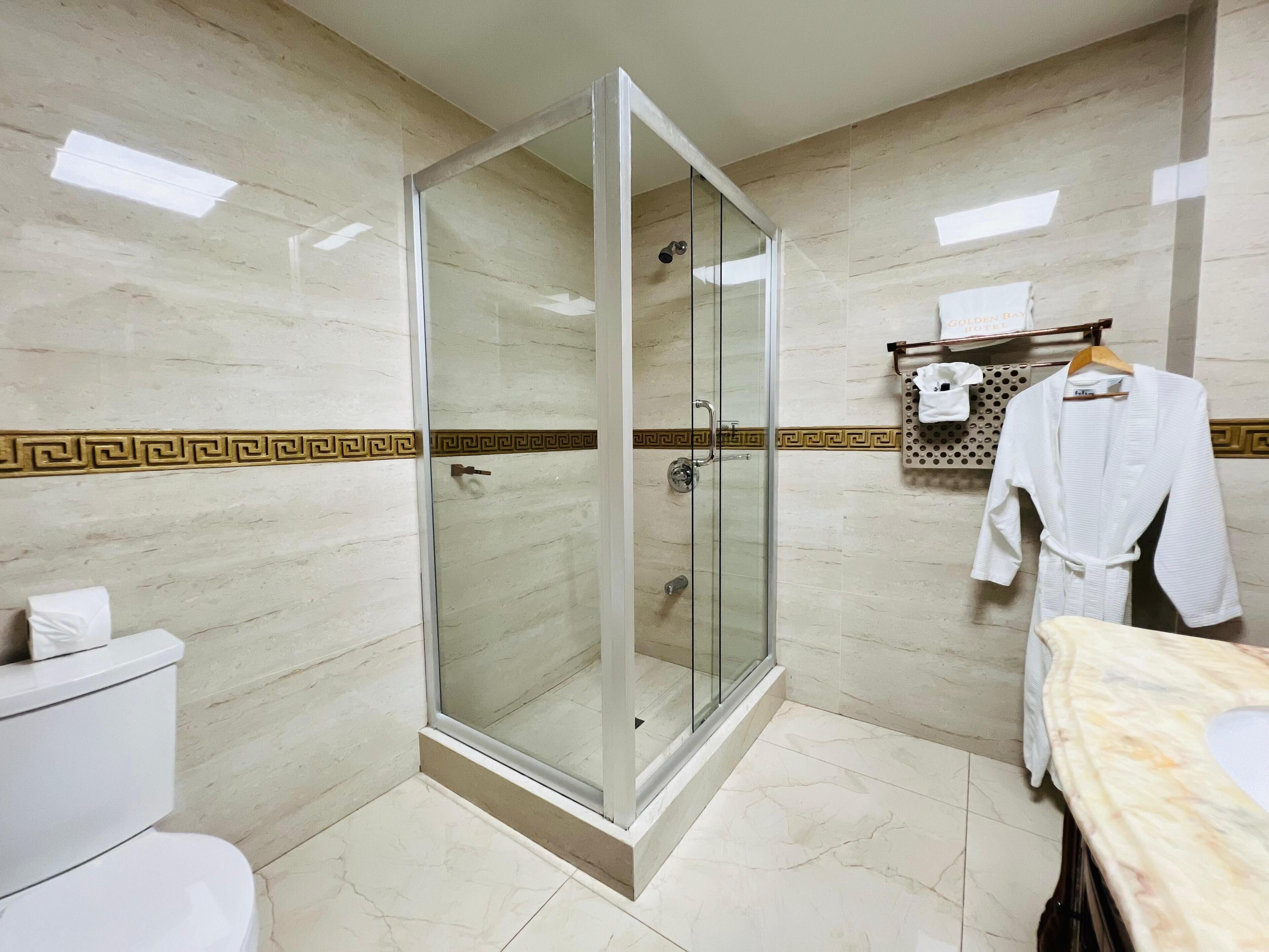 A modern bathroom with a glass-enclosed shower, marble walls, and a white toilet.