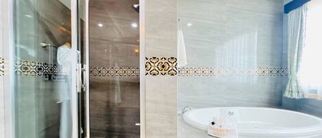 A modern bathroom with a glass shower enclosure, a bathtub, and decorative tile borders.
