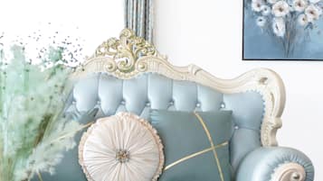 A light blue upholstered sofa with gold trim and a tufted backrest, positioned against a white wall with a framed floral painting.