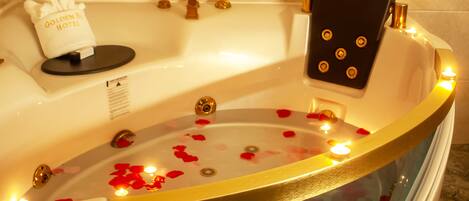 Una bañera con pétalos de rosa y velas, una toalla y una botella de champú.