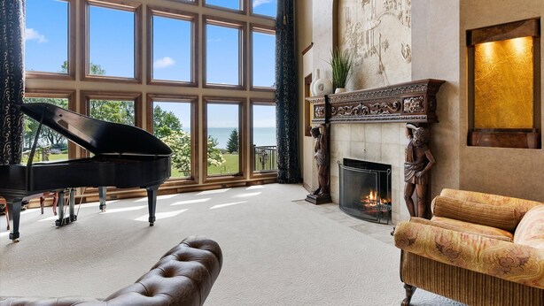 A grand room with a piano, a fireplace, and a large window overlooking a scenic view. - Amazing Luxury Mansion ~ Indoor Pool ~ Stunning Lake Views ~ One Of A Kind! (Newton)