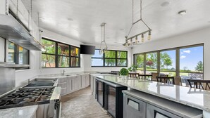 A modern kitchen with stainless steel appliances, a large island, and a view of the outdoors. - Amazing Luxury Mansion ~ Indoor Pool ~ Stunning Lake Views ~ One Of A Kind! (Newton)