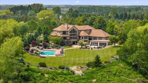 A large house with a swimming pool, surrounded by lush greenery and a well-maintained lawn. - Amazing Luxury Mansion ~ Indoor Pool ~ Stunning Lake Views ~ One Of A Kind! (Newton)