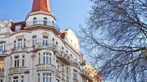 A multi-story building with a prominent red-topped tower, ornate balconies, and a clear sky. - Charming river apartment, Castle view, Breakfast incl. (Praha 5)