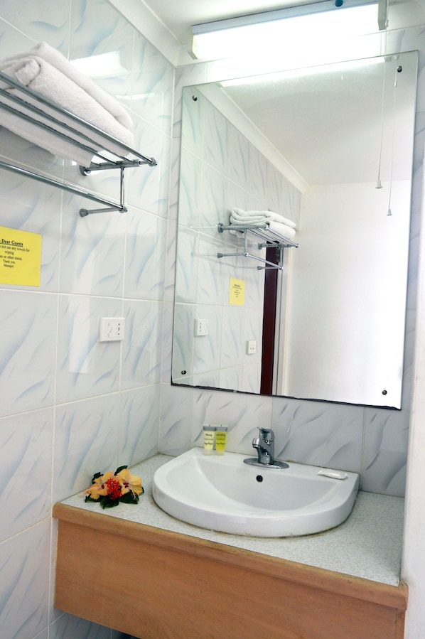 Un baño con un lavabo blanco, un espejo y un perchero para toallas.