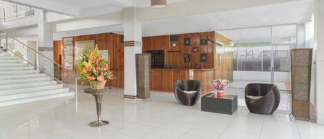 A spacious lobby with a staircase, modern furniture, and a reception desk.