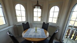 A dining area with a round table, four chairs, a bottle of wine, and a chandelier. - Vacation apartment type 1, 50sqm, 1 bedroom - Ferienhaus Irene (Vogtsburg im Kaiserstuhl)