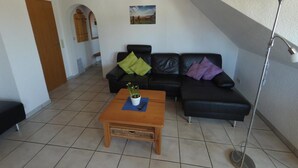 A living room with a wooden coffee table, black leather sofas, and a floor lamp. - Vacation apartment type 1, 50sqm, 1 bedroom - Ferienhaus Irene (Vogtsburg im Kaiserstuhl)