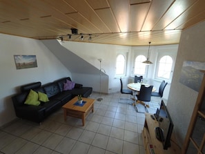 A living room with a black sofa, a wooden coffee table, and a dining area with a table and chairs.