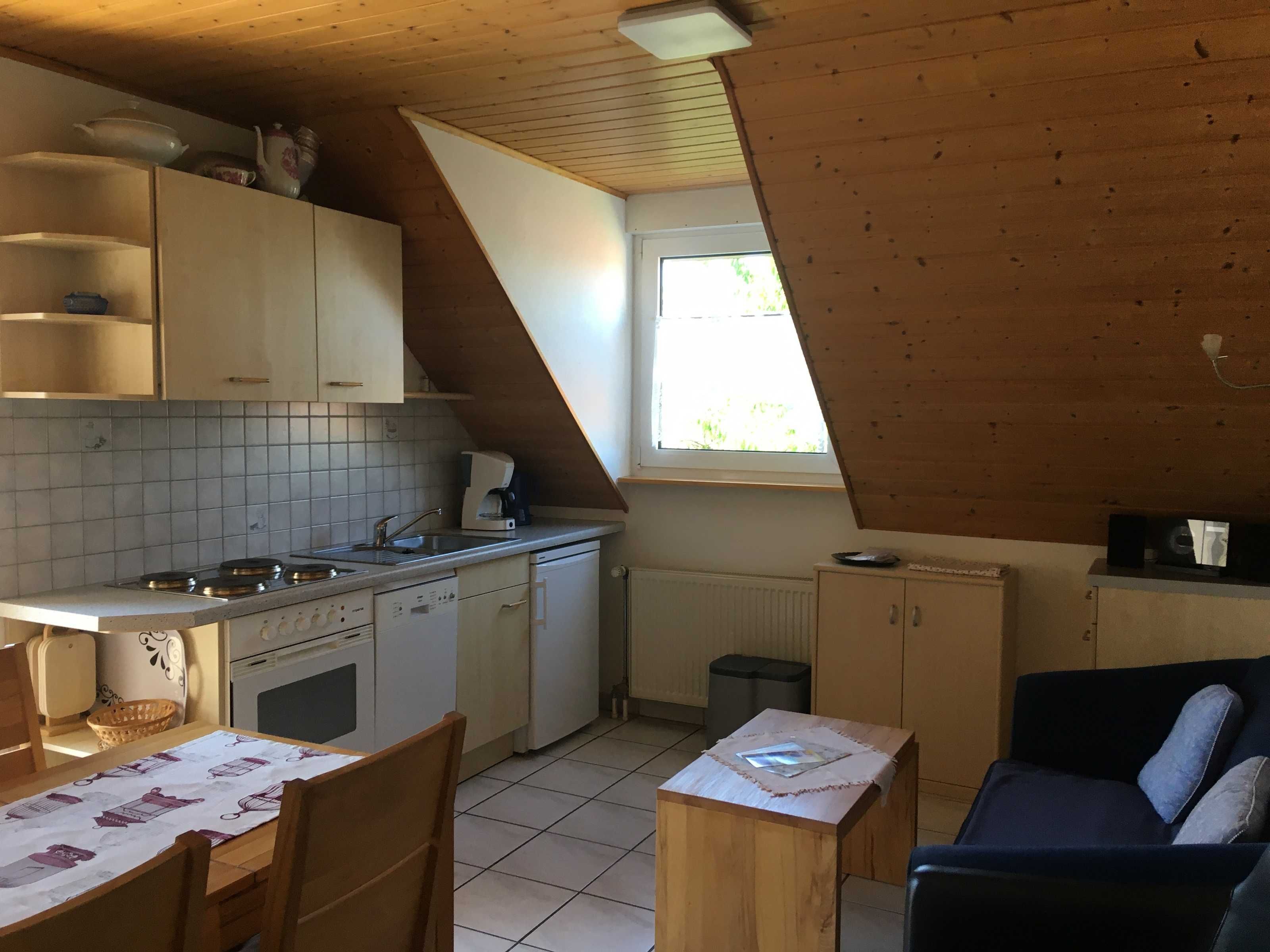 Cocina compacta con comedor, techo de madera y ventana que proporciona luz natural.