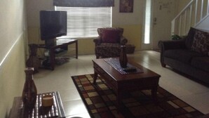 A living room with a television, a sofa, a chair, and a coffee table.