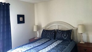 A bedroom with a bed, two bedside tables, a ceiling fan, and a wall-mounted picture.