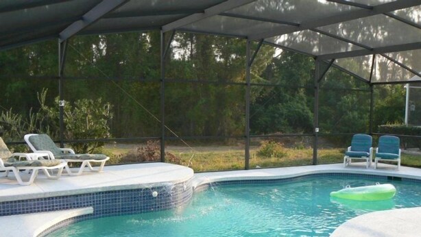 A covered swimming pool with lounge chairs and a hot tub.