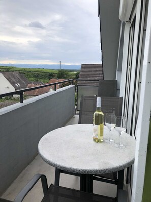 A balcony with a round table, a bottle of white wine, and two glasses.