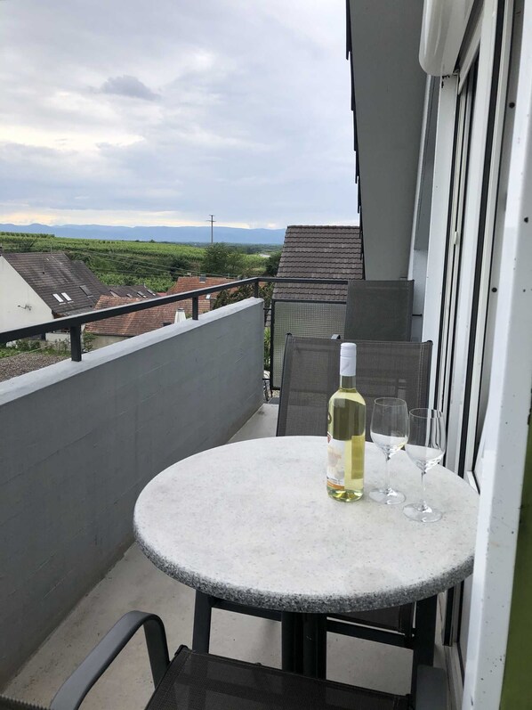A balcony with a round table, a bottle of white wine, and two glasses.