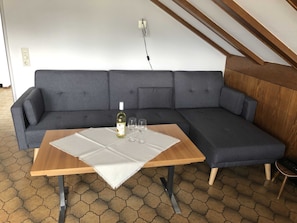 A modern living room with a grey sectional sofa, a wooden coffee table, and two wine glasses.