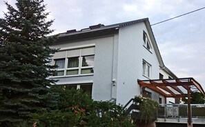A modern two-story house with a sloped roof, large windows, and a covered porch area.