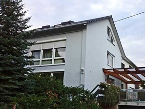 A two-story building with a white exterior, large windows, and a visible balcony.