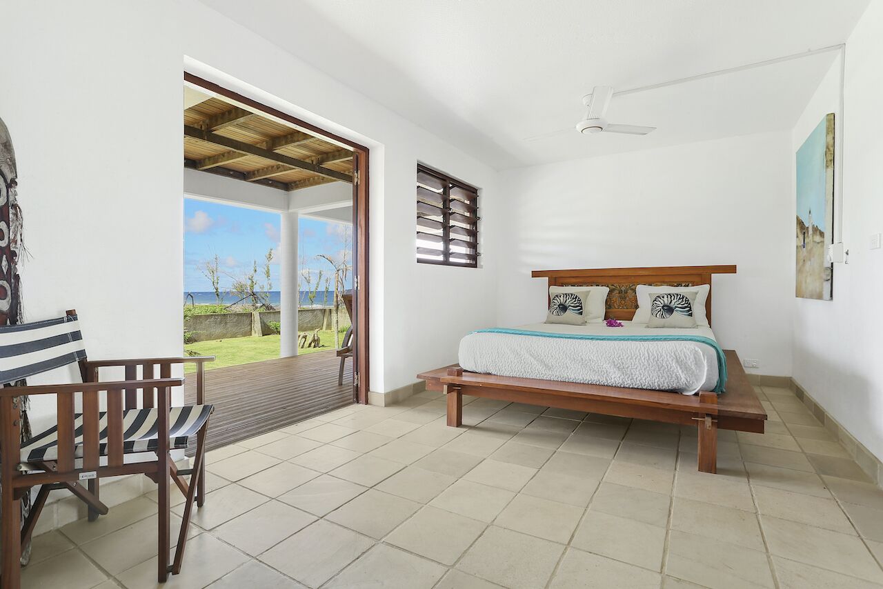 A bedroom with a bed, a chair, a window, and a view of the outdoors.