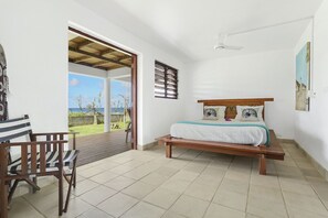 A bedroom with a bed, a chair, a window, and a view of the outdoors.