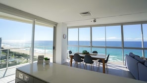 Enjoy panoramic ocean and city views from this spacious room with a central dining table, comfortable seating, and kitchenette.