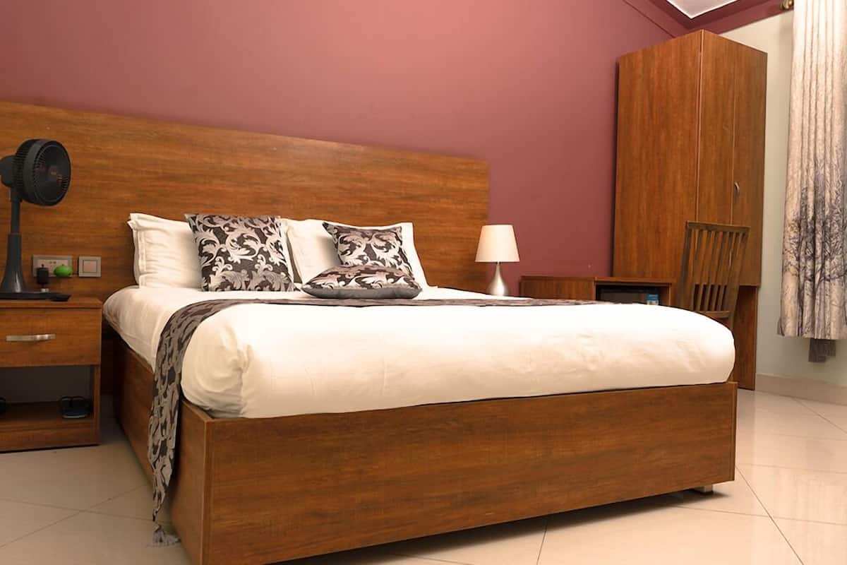 A bedroom with a wooden bed, a nightstand, a lamp, and a wardrobe.
