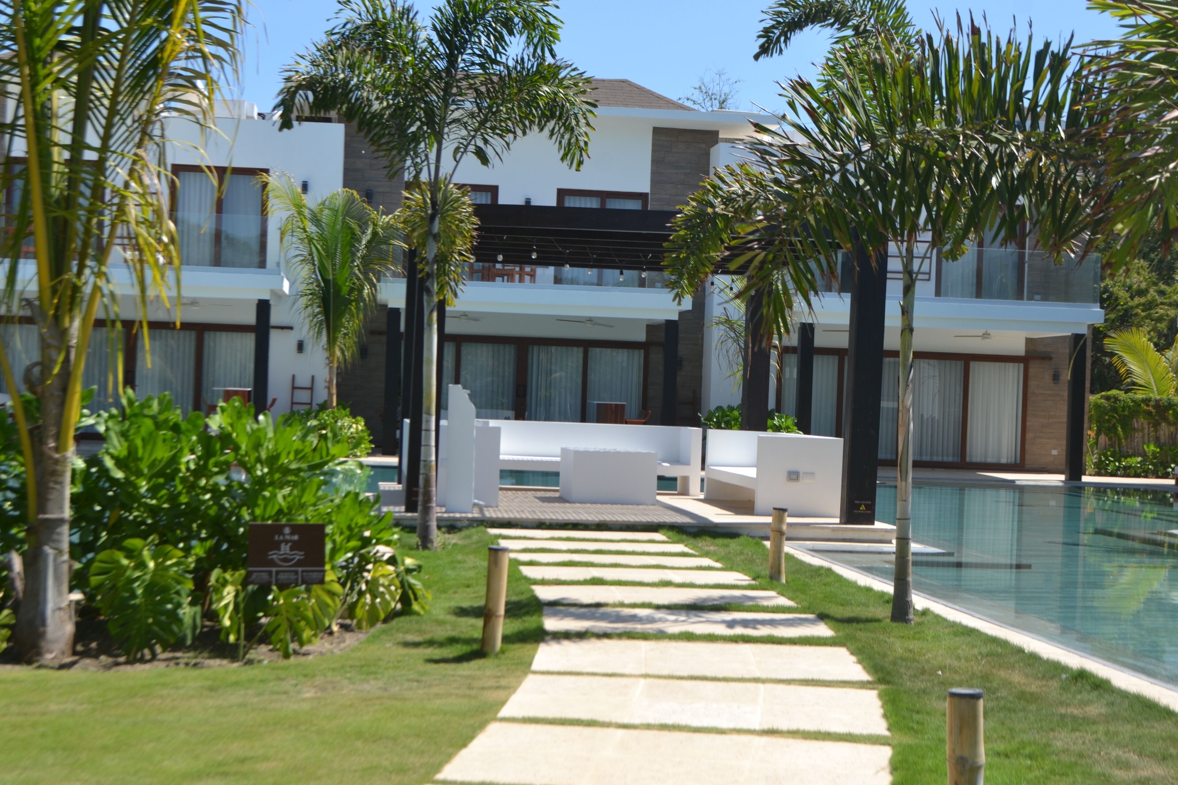 Un hôtel moderne doté d’une piscine, entouré de palmiers et d’une pelouse bien entretenue.