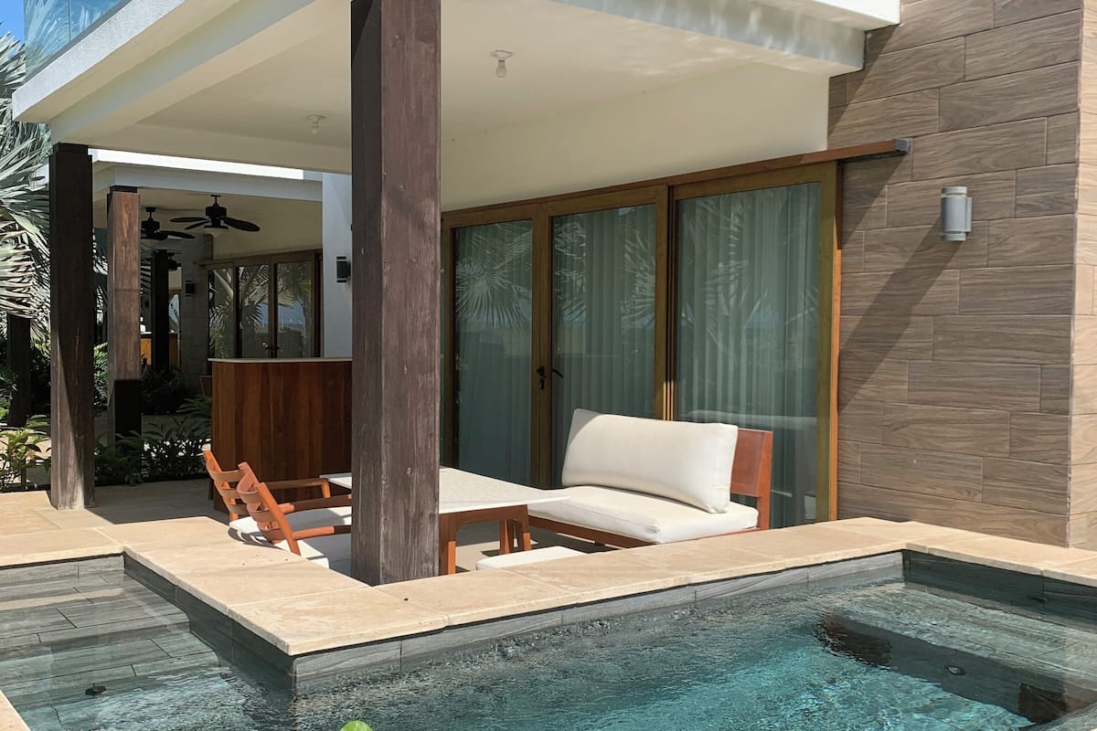 Una casa moderna con piscina, terraza de madera y zona de estar al aire libre.