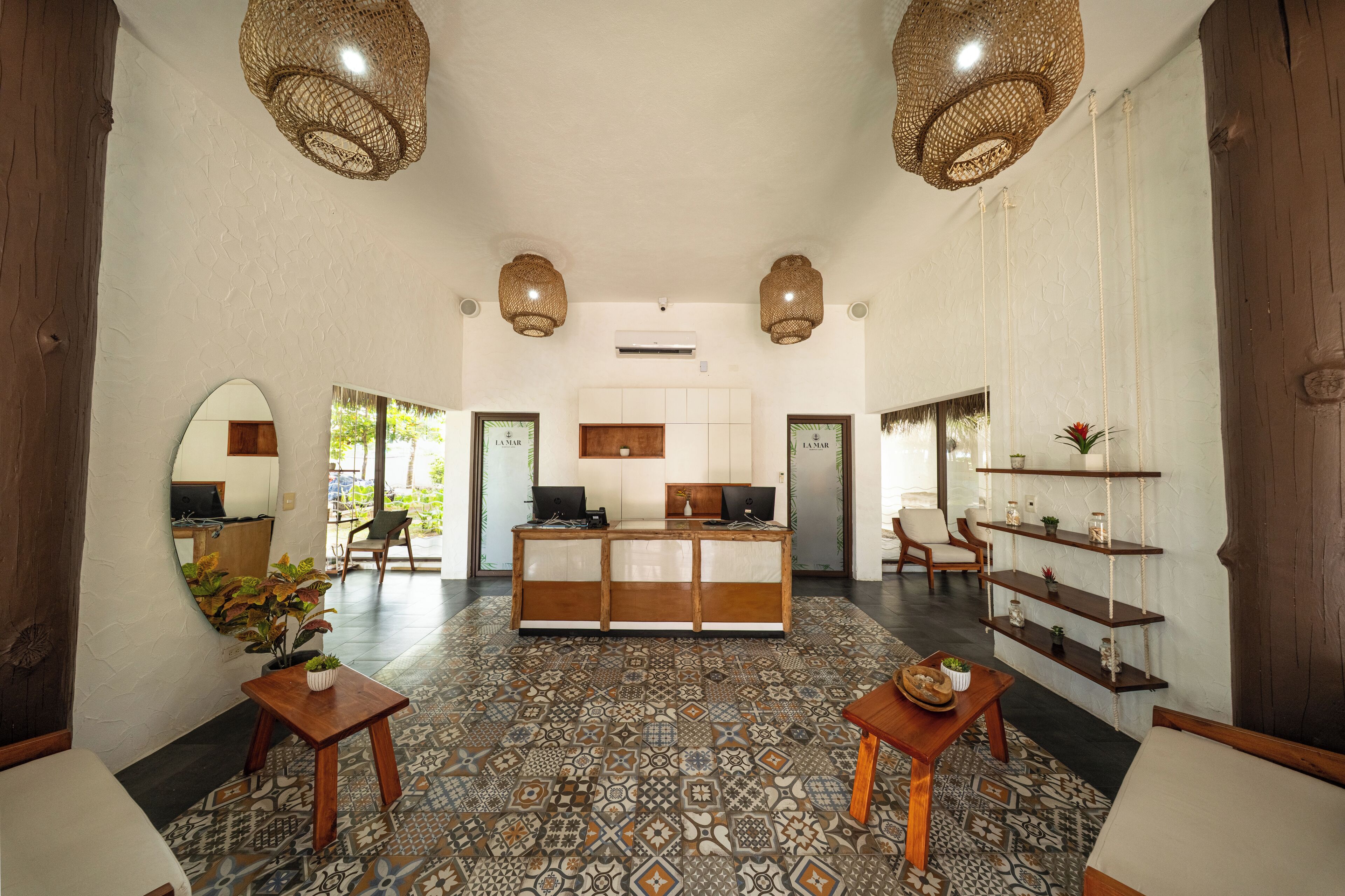 A reception area with a wooden desk, two chairs, a mirror, and a patterned floor.