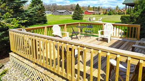 A wooden deck with outdoor furniture, a lawn, and houses in the background. - Copal on Lake Shore @ Spring Brook Resort (Wisconsin Dells)