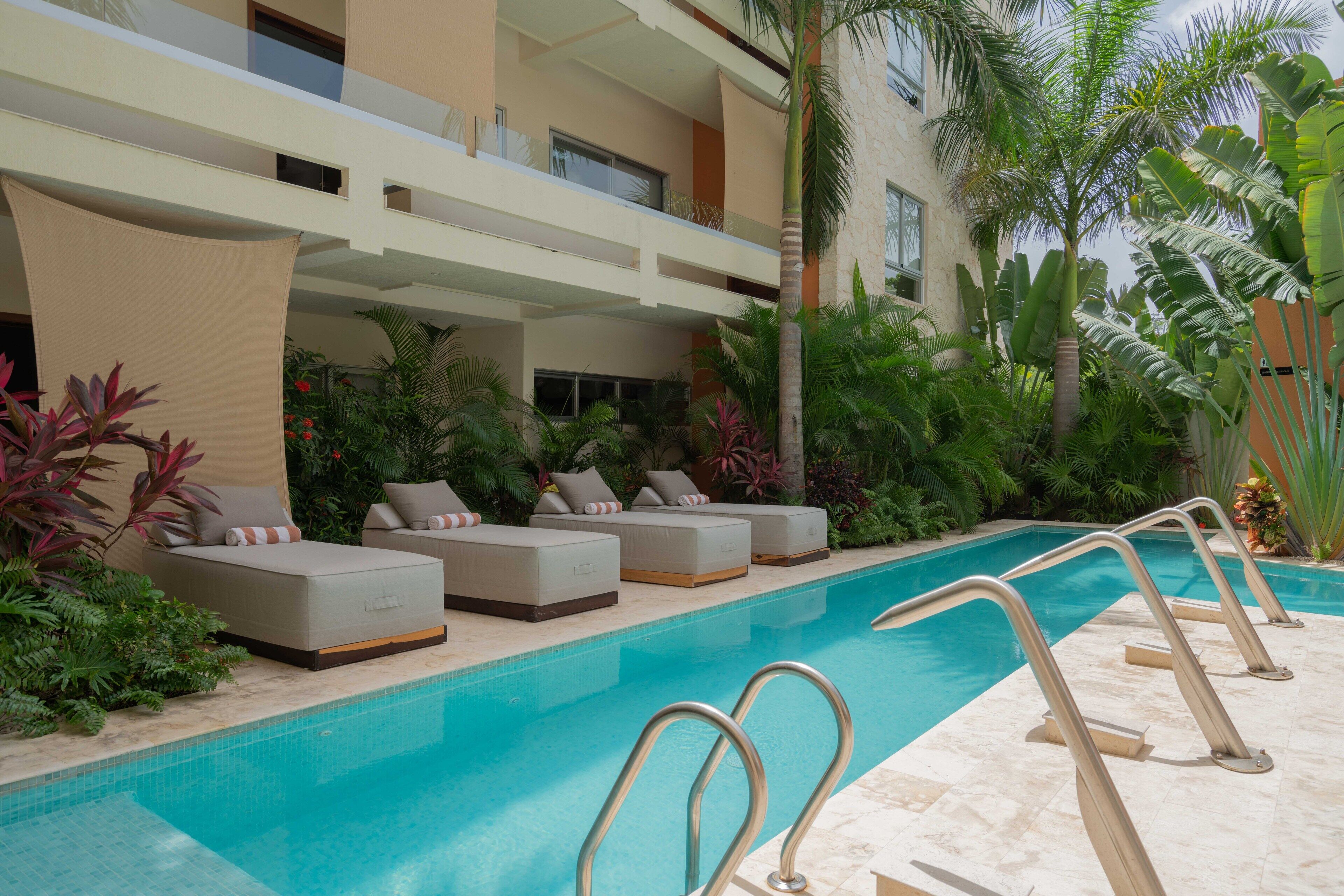 Un espace piscine doté de chaises longues et d’une piscine à l’eau d’un bleu cristallin.