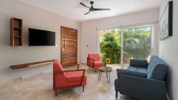 A modern living room with a flat-screen TV, two sofas, a wooden shelf, and a ceiling fan.