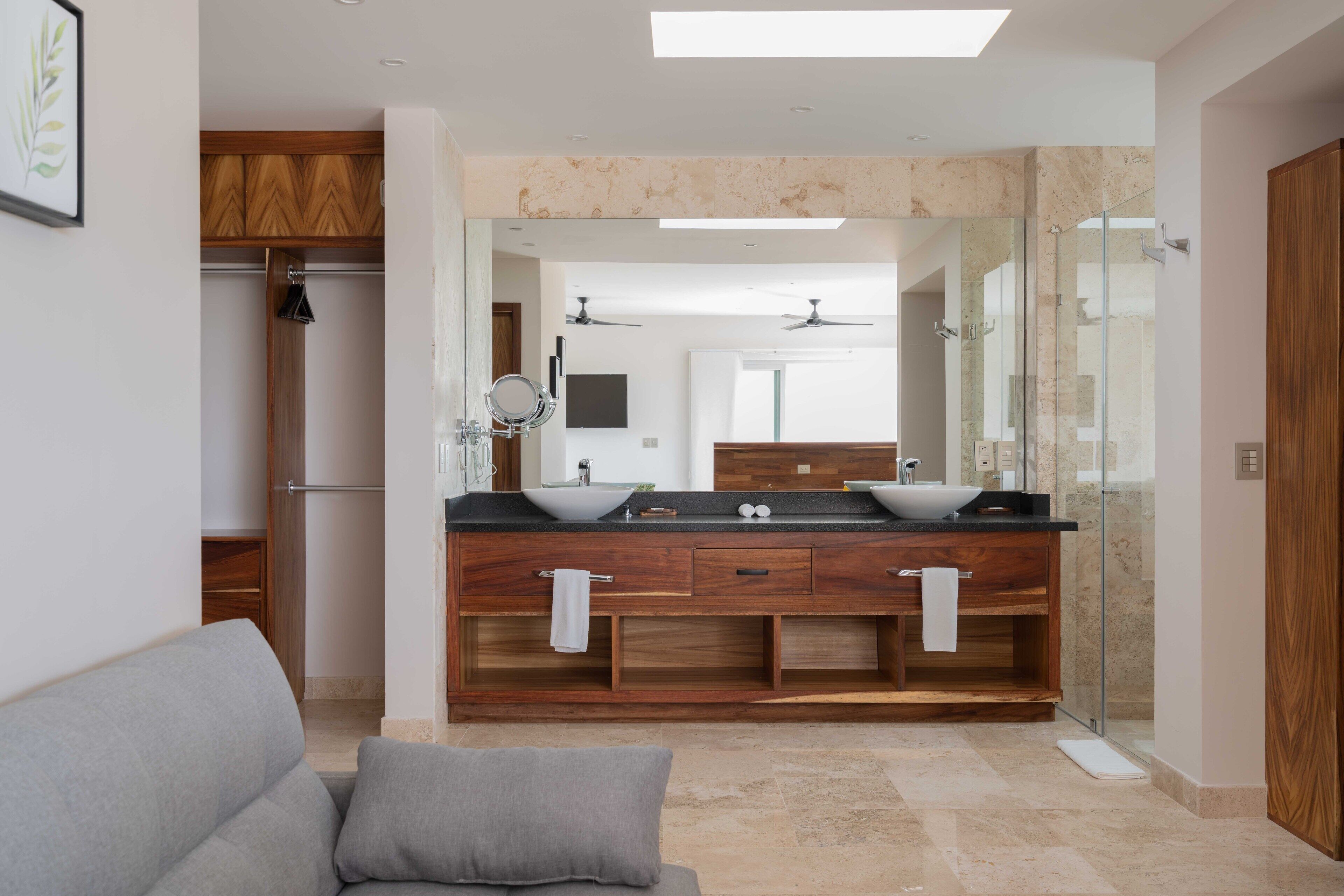 Une salle de bain moderne dotée d’un meuble-lavabo à deux vasques, d’une cabine de douche en verre et d’un miroir encastré.