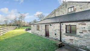 A stone building with a sloped roof, a fenced yard, and a grassy area. - 4 bedroom accommodation in Inglewhite, near Longridge (Inglewhite, near Longridge)