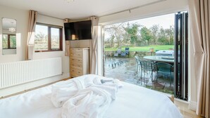A bedroom with a bed, a TV, a dresser, and a view of an outdoor patio with chairs and a table. - 4 bedroom accommodation in Inglewhite, near Longridge (Inglewhite, near Longridge)