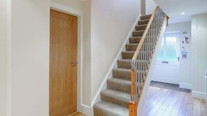 A staircase with wooden handrails and carpeted steps leading to a door with a wooden panel. - 4 bedroom accommodation in Inglewhite, near Longridge (Inglewhite, near Longridge)