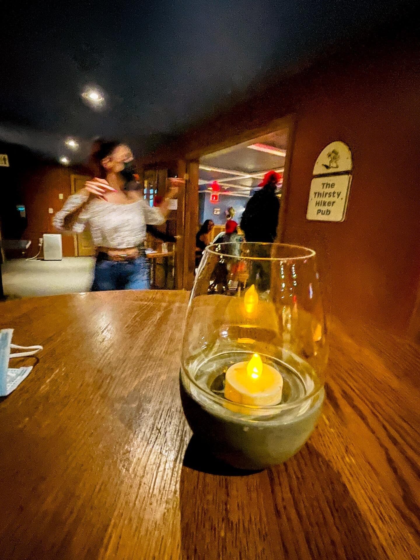 Et lys i et glas på et træbord i en pub.
