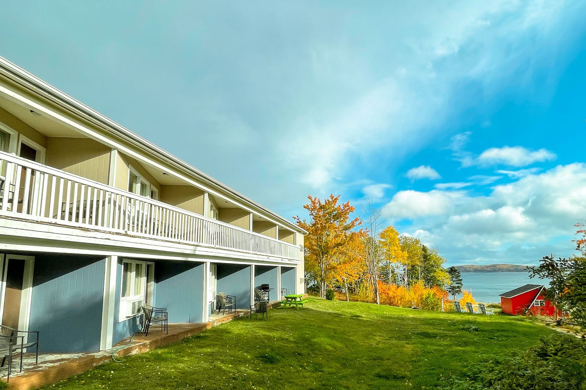 A two-story hotel with a covered outdoor area and a view of a lake.
