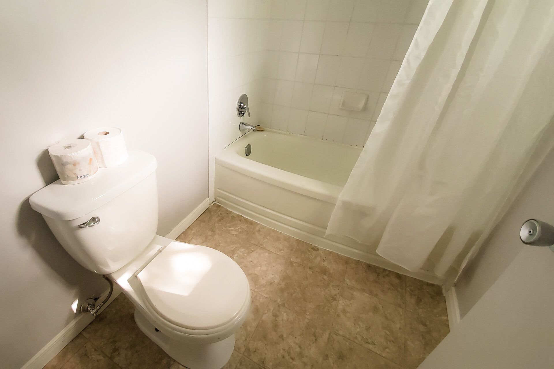 A bathroom with a toilet, a bathtub, and a shower curtain.