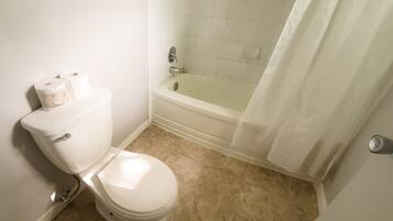 A bathroom with a toilet, a bathtub, and a shower curtain.