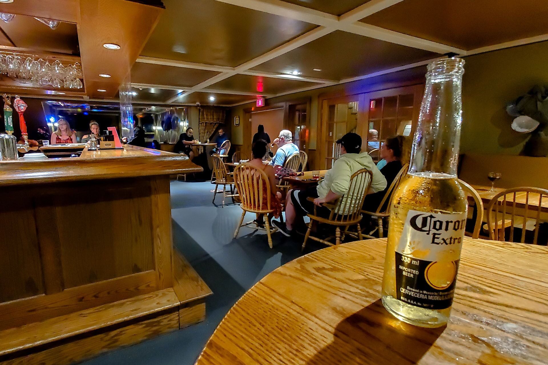 A bar area with wooden furniture and a bottle of Corona Extra beer on a table.