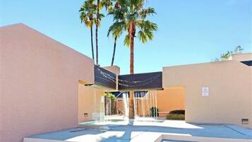 A modern building with a water feature in front, palm trees, and a clear sky.