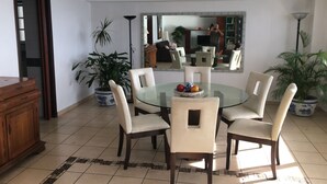 A dining area with a round glass table, four chairs, and a ceiling fan.