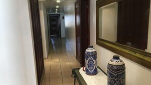 A hallway with a tiled floor, a wooden door, and two decorative vases on a table.