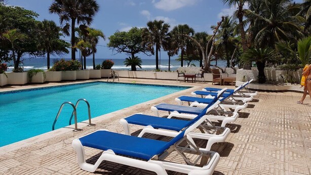 A poolside area with lounge chairs and a view of the ocean.