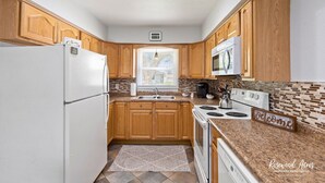 A kitchen with wooden cabinets, a white refrigerator, a stove, and a microwave.