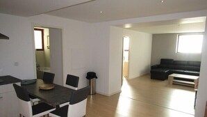 A modern living space with a dining area, a black sofa, and a wooden floor. - Nice and spacious ground floor appartment close to the beach (LACANAU OCEAN)