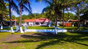 A tropical resort with a red-roofed building surrounded by palm trees and a grassy area. - Beachfront House in Playa Tivives with private pool (Tivives)