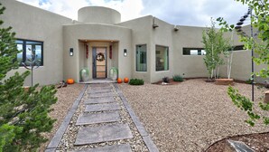 Ein modernes Haus mit einem Kiesweg, der zum Eingang führt, umgeben von Kies und kleinen Pflanzen.