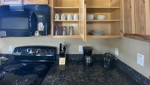 Eine Küche mit einem schwarzen Herd, einer Mikrowelle, einer Kaffeemaschine und Holzausbau.